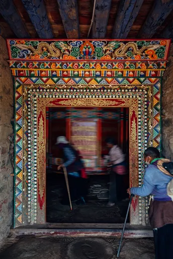 一位妇女站在一座古老寺庙内的彩色房间入口处