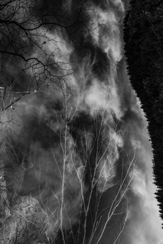 天空中的黑白云朵和水边树木