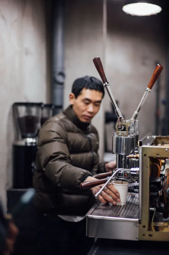 在一家咖啡店工作的男子正在制作一杯咖啡。