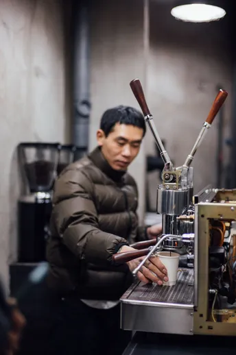 在一家咖啡店工作的男子正在制作一杯咖啡。