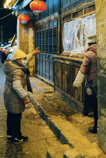 一个男人和一个女人站在夜晚的巷子里 周围有古老的建筑和灯笼。