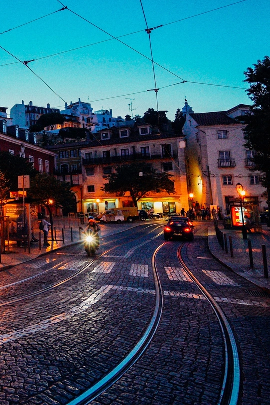 夜晚行驶在街道上的火车 轨道上有汽车 背景有建筑物。