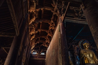 一尊金佛雕像站在一座寺庙内的大型房间里