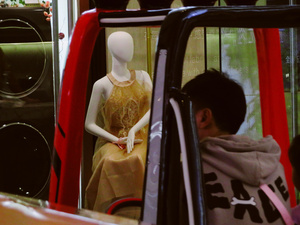 一个模特儿坐在车内看着站在窗边的女子