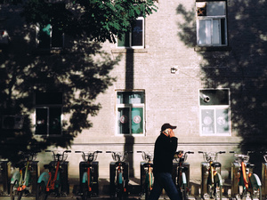 一个在人行道上行走的男子正在打电话 旁边停着自行车。