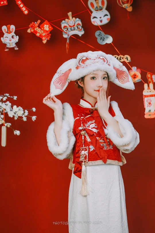 一位穿着红色连衣裙和帽子 站在红色背景前的年轻女子