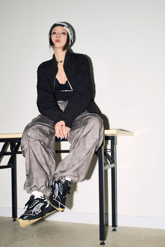 一位穿着全黑衣服的年轻女子坐在桌子旁的一把椅子上。