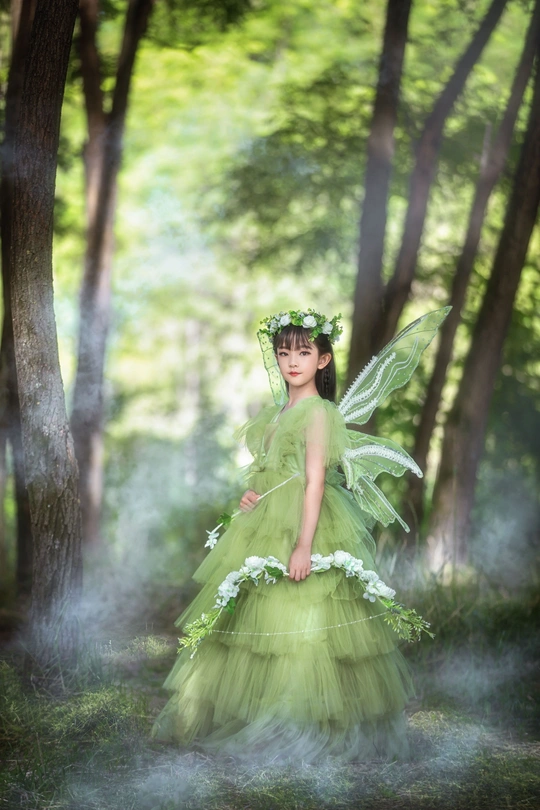美丽的女人穿着绿色衣服在树林里打扮成仙女