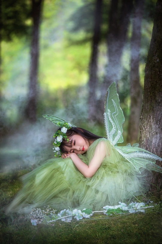 树林里一个长着绿色翅膀、打扮成仙女的小女孩