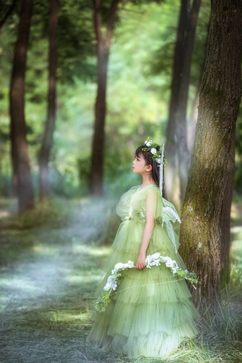 一位身穿绿色连衣裙的年轻女子穿过一片绿树成荫的森林