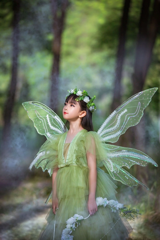 树林里一个长着绿色翅膀、打扮成仙女的小女孩