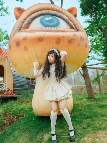 站在大型充气眼睛前面的穿着裙子的女孩