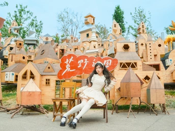 一个年轻女子坐在一个小椅子上 前面有一个展示微型木屋的架子。