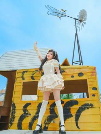 一位穿着白色连衣裙和靴子的年轻女子在模型房前摆姿势