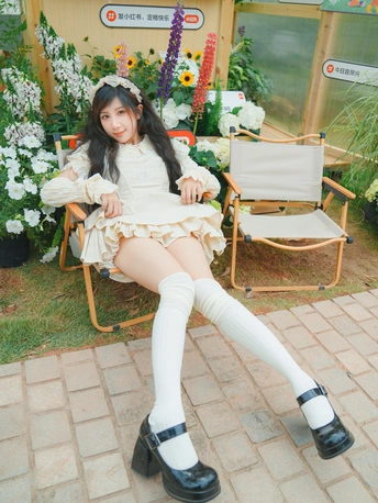 一位穿着白色连衣裙和过膝长袜的年轻女子坐在椅子上