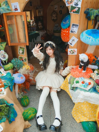 一个穿着白色连衣裙的小女孩坐在一个玩具满屋的娃娃屋中