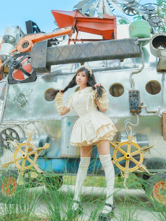 一个穿着白色连衣裙和靴子的年轻女子站在田野中