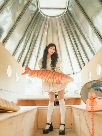 一位年轻女子手持一条大鱼站在室内