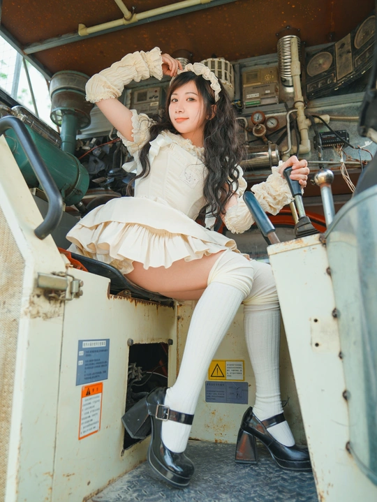 一个穿着白色连衣裙的年轻女子坐在一辆旧车辆内部