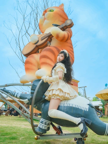 一个小女孩坐在公园里一尊大雕像的顶部