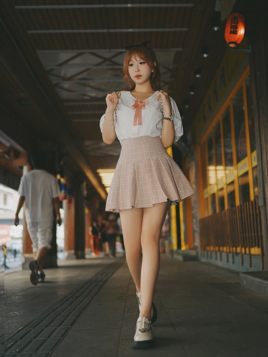 一位穿着短裙和粉色连衣裙的年轻女子正在火车站走廊里走动。