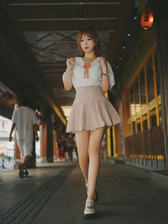 一位穿着短裙和粉色连衣裙的年轻女子正在火车站走廊里走动。