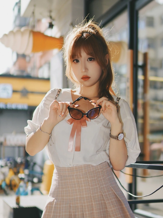 一位穿着连衣裙和裙子的年轻女子举起太阳镜