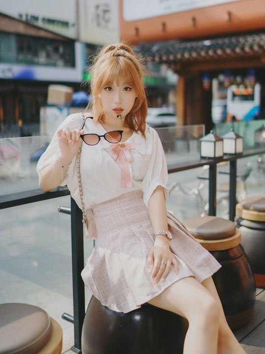 一个戴眼镜穿裙子的年轻女子坐在椅子上