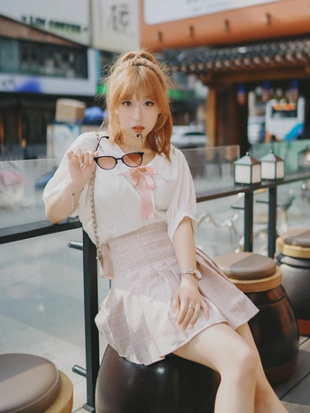 一个戴眼镜穿裙子的年轻女子坐在椅子上