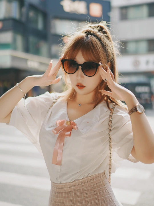 一位穿着白色衬衫和裙子的年轻女子在街上。