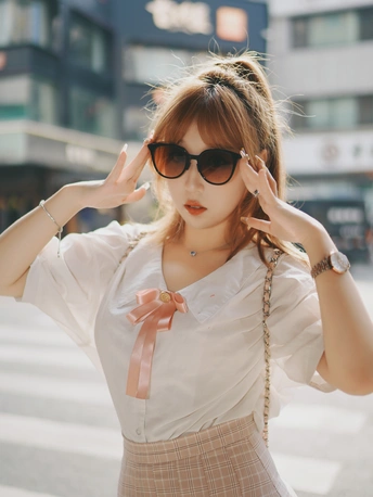 一位穿着白色衬衫和裙子的年轻女子在街上。