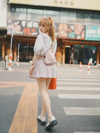 一位穿着连衣裙的年轻女子穿越人行横道。