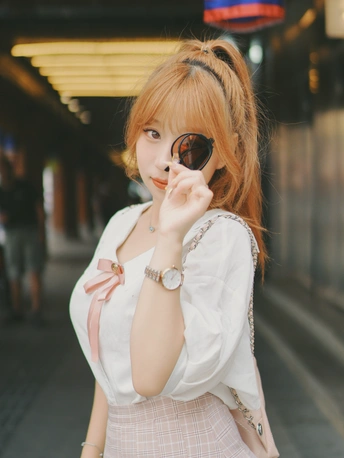 一位戴着太阳镜和白色裙子的年轻女子站在街上