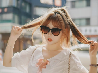 一位穿着白色衬衫和太阳镜在街上的女人