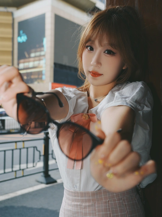 一位戴着太阳镜的年轻女子正在为相机摆姿势