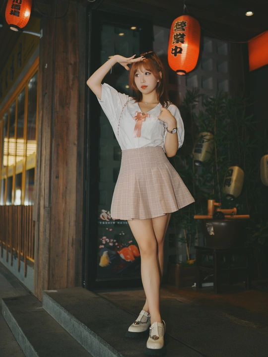 一位穿着裙子的年轻女子站在一栋建筑前