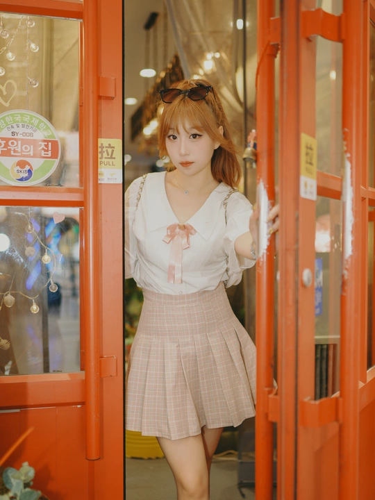 一位穿着连衣裙的年轻女子站在红色门前