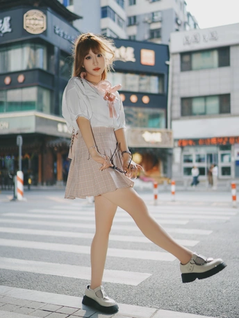 一位穿着连衣裙的年轻女子穿越城市中的人行横道