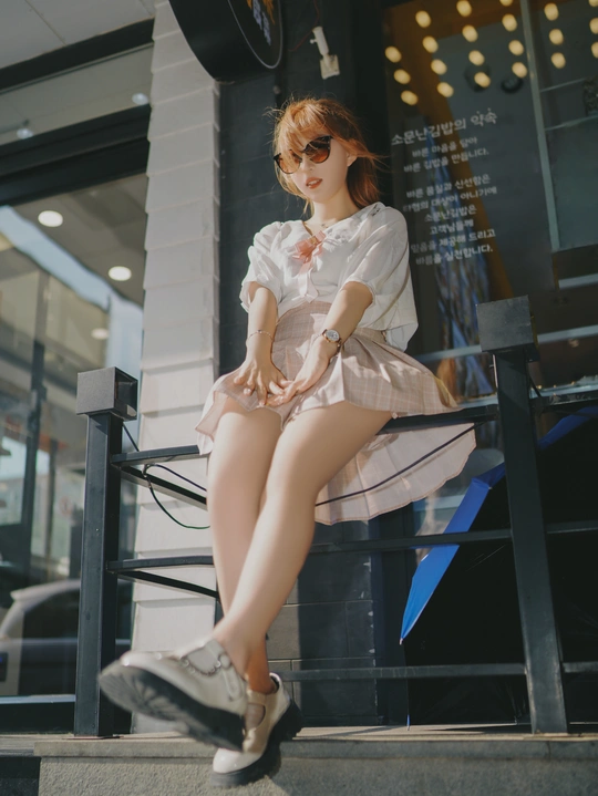 一个穿着连衣裙的年轻女子坐在长凳上 双腿交叉。