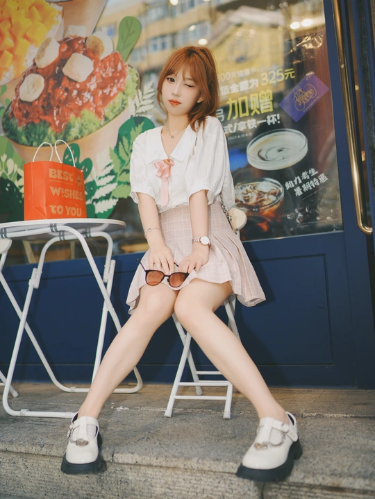 一位年轻女子坐在街上一把白色的椅子上