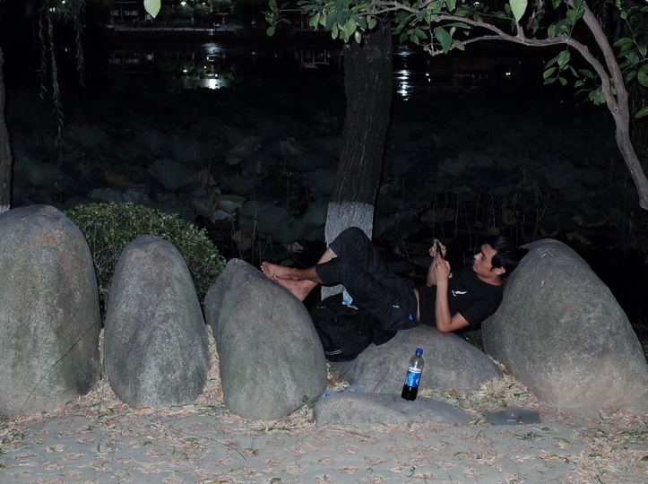 几个人躺在一些大石头上 一名男子晚上用手机拍照