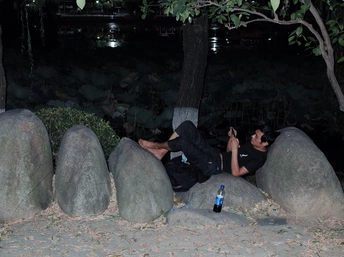 几个人躺在一些大石头上 一名男子晚上用手机拍照