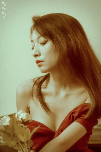 一位穿着红裙子的美丽年轻女士手里拿着一朵玫瑰。