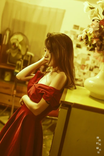 一位穿着红裙子的年轻女子站在一个房间里的梳妆台旁边。