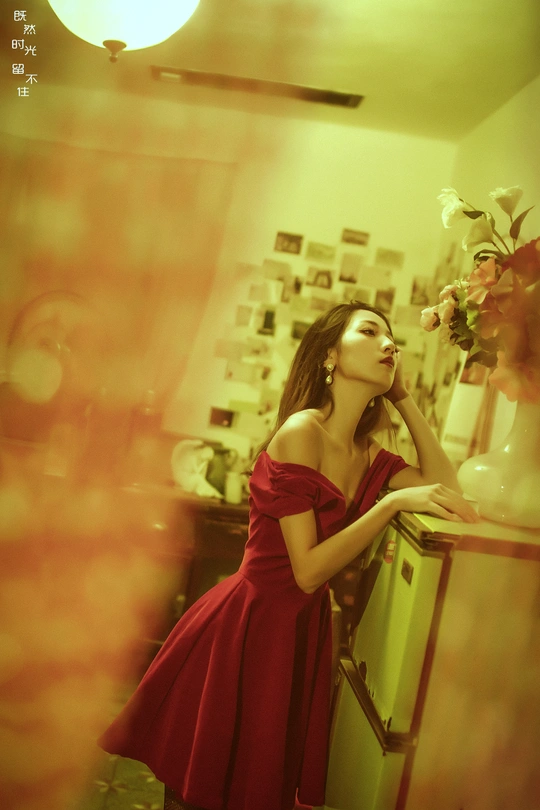 一位穿着红裙子的年轻女子站在一个有花瓶的房间里