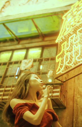 一个穿着红裙子的年轻女子站在一个有霓虹灯在嘴上方的建筑物前