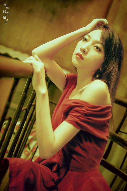 一位穿着红裙子的年轻女子坐在椅子上为模特摆姿势