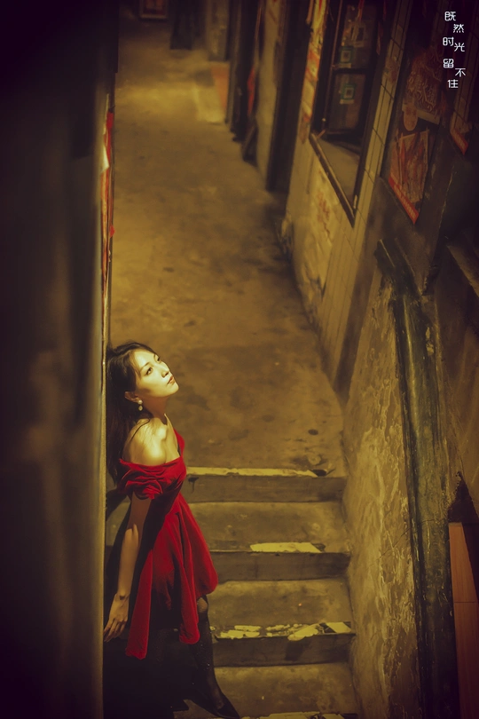 一个穿红裙子的年轻女子走下小巷的楼梯 楼梯上站着一位穿长红裙子的女子。