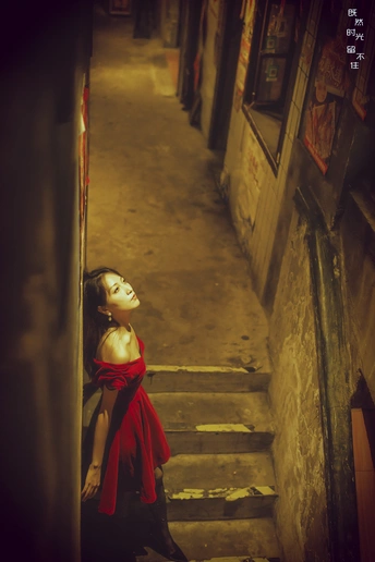 一个穿红裙子的年轻女子走下小巷的楼梯 楼梯上站着一位穿长红裙子的女子。