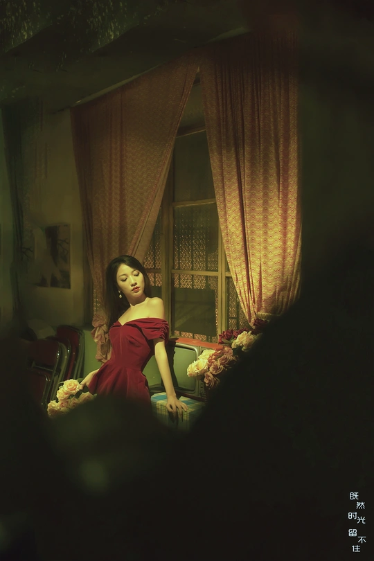 一位穿着红裙子的年轻女子站在一个有镜子和椅子的房间里